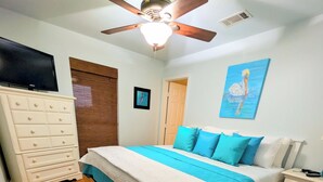 Ein Schlafzimmer mit Bett, Kommode, Deckenventilator und einem Bild an der Wand.