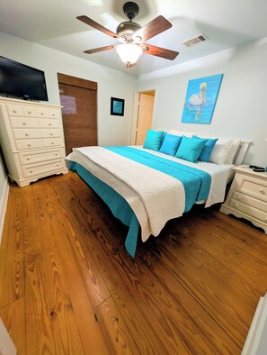 Ein Schlafzimmer mit Bett, Kommode, Deckenventilator und einem Bild an der Wand.