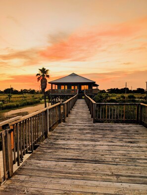 Un muelle de madera que lleva a un edificio con techo, rodeado de paisaje natural.
