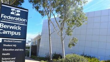 A sign for Federation University Australia Berwick Campus with a modern building in the background.