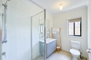A bathroom with a glass shower enclosure, a sink, a toilet, and a window with a view. - Modern Clyde House Smart TVDryer (Clyde)