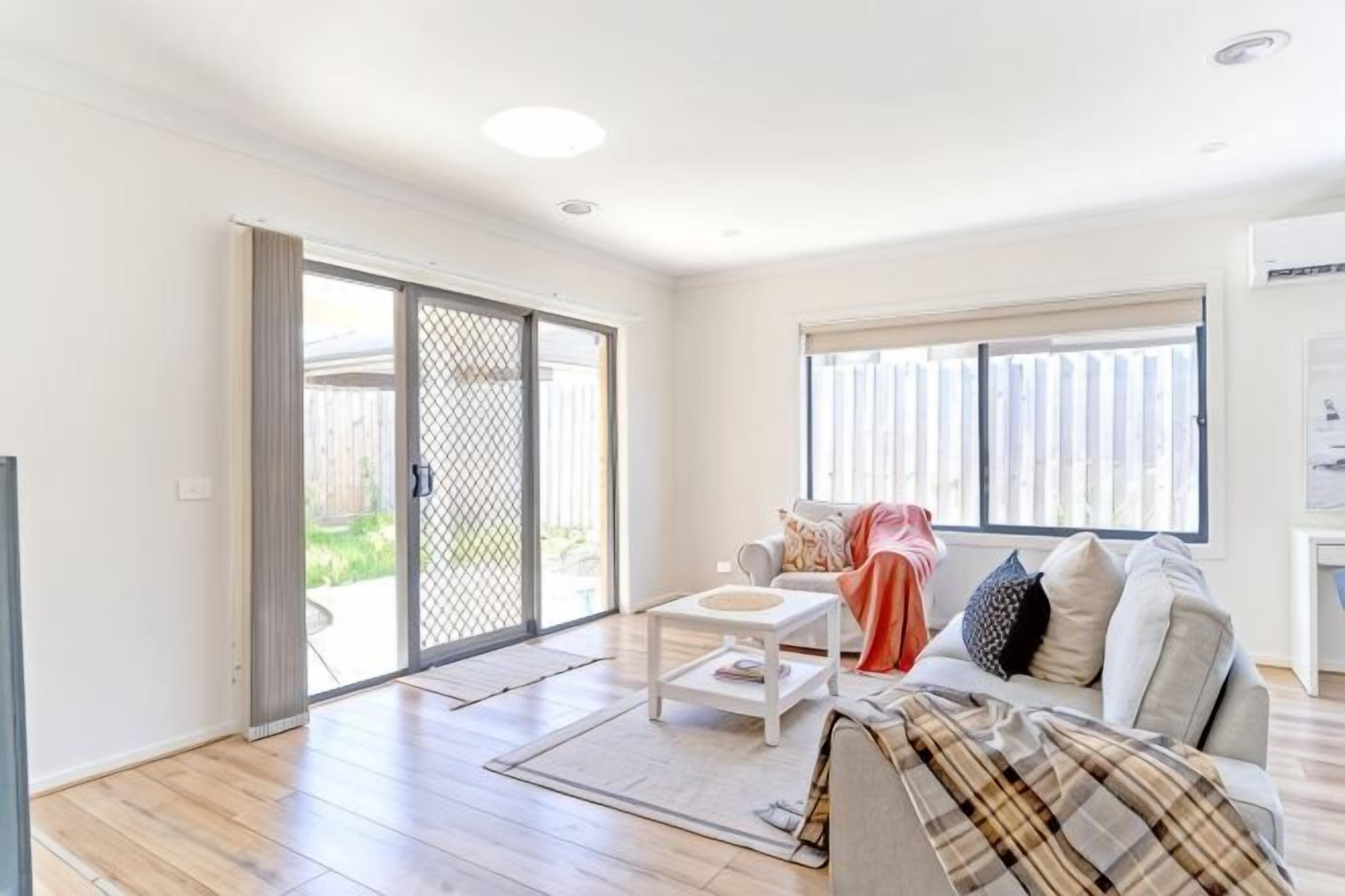 A living room with a sofa, coffee table, and a sliding glass door leading to an outdoor area.