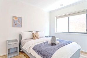 A bedroom with a bed, a nightstand, a window, and a wall art piece. - Modern Clyde House Smart TVDryer (Clyde)