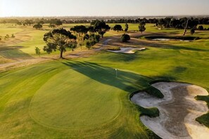 A golf course with sand bunkers, trees, and a flagstick. - Modern Clyde House Smart TVDryer (Clyde)