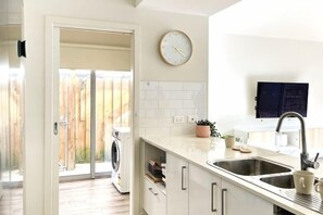 A kitchen with a sink, countertop, and a clock on the wall. - Stylish Berwick Home with WiFi, Smart TV, Garage (Berwick)