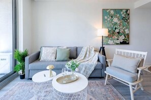 Ein Wohnzimmer mit Sofa, Sessel, Couchtisch und einem Gemälde an der Wand.