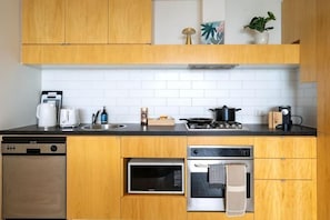 A modern kitchen with wooden cabinets, a built-in oven, a microwave, and a coffee maker. - lvl42 2B APT with Free Parking in CBD (Melbourne)