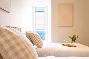 Ein Schlafzimmer mit einem Bett, einem Fenster und einem gerahmten Bild an der Wand.
