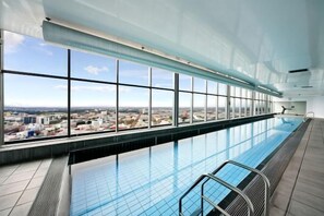 An indoor swimming pool with a city view, large windows, and a tiled floor. - lvl42 2B APT with Free Parking in CBD (Melbourne)