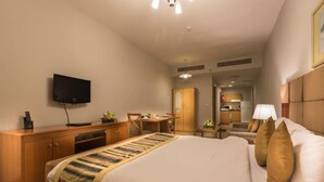 A hotel room with a bed, a desk, a television, and a wardrobe. - City Stay Grand Hotel Apartments - Al Barsha (Dubai)