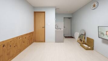 Un corridoio con una porta in legno, un lavandino e uno specchio appeso al muro.