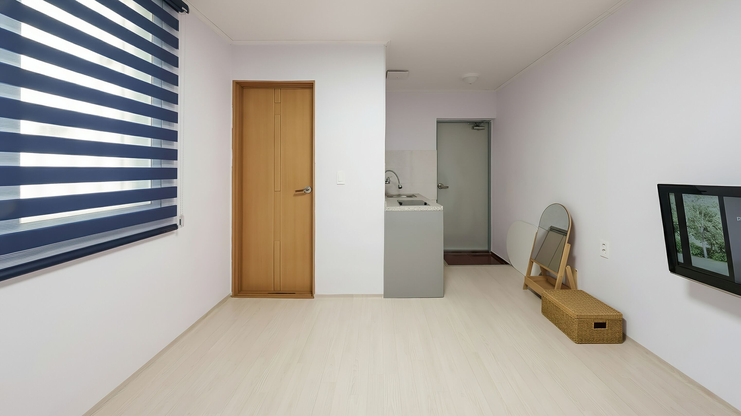A hallway with a wooden door, a bathroom with a sink, and a framed mirror on the wall.