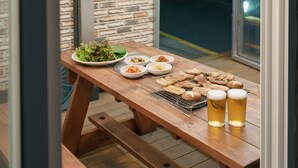 Una mesa de madera con diversos platos, entre ellos una ensalada, kimchi y pan, y dos vasos de cerveza.