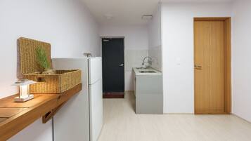 Una cocina compacta con refrigerador, lavamanos y puerta de madera.