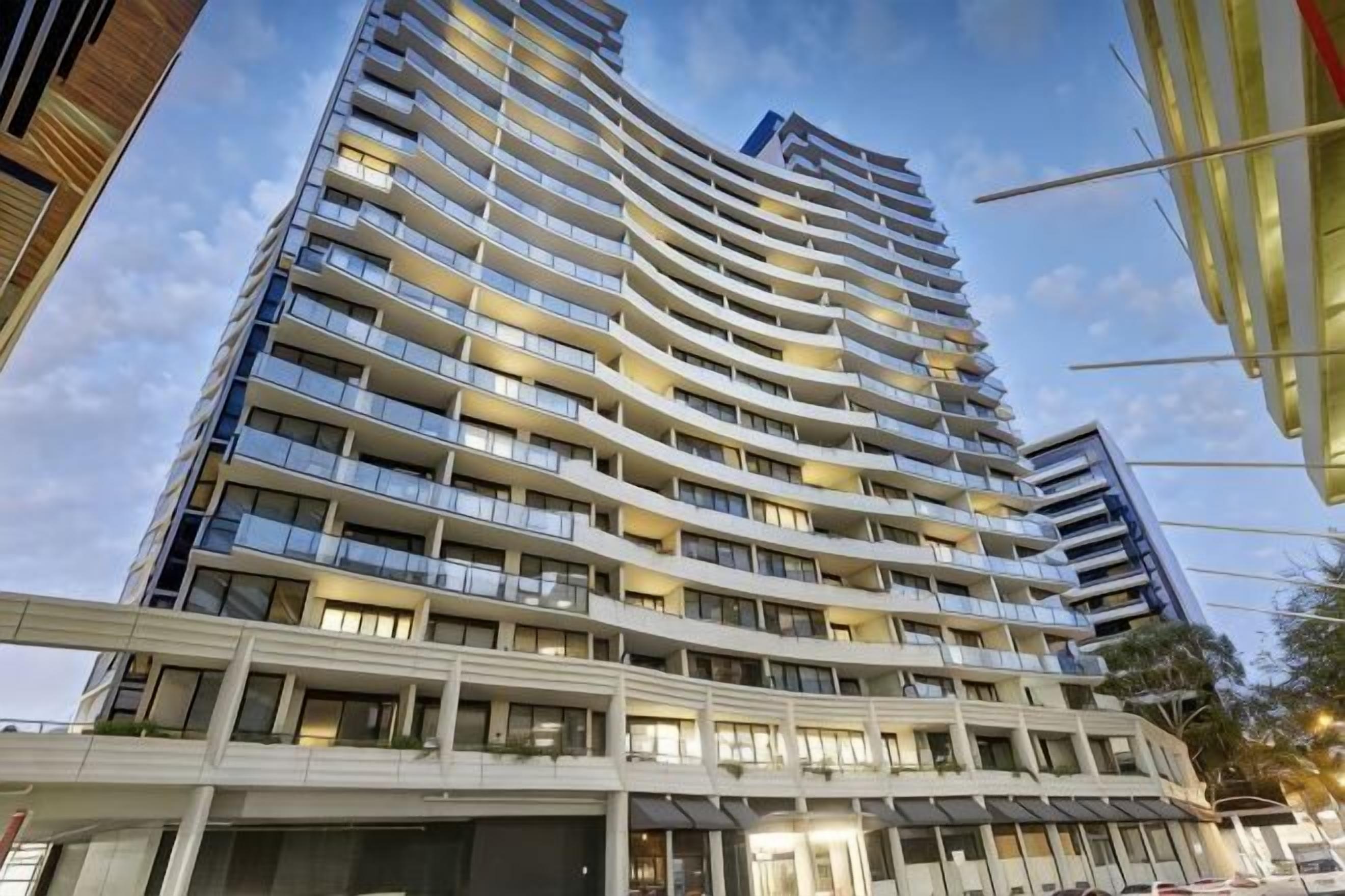 A high-rise hotel with multiple balconies, a modern architectural design, and a clear sky.