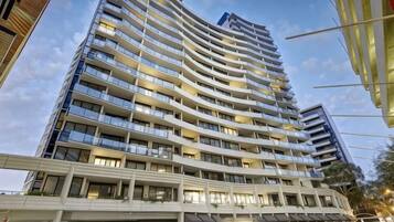A high-rise hotel with multiple balconies, a modern architectural design, and a clear sky.