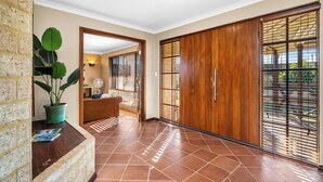 A spacious hallway with a tiled floor, a wooden wardrobe, and a potted plant. - Spacious 5-bedroom house with pool and park access  in serene Ocean Reef with AC (Ocean Reef)