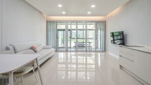 Uma sala de estar moderna com sofá, mesa de jantar e área de cozinha, incluindo uma televisão.