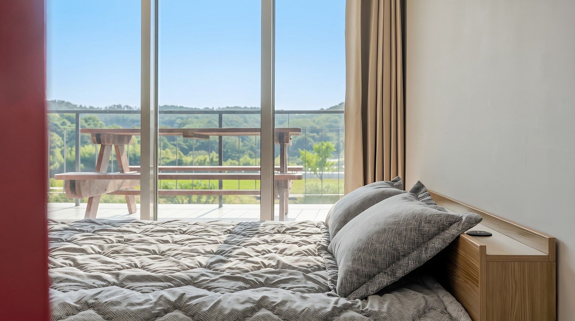 A bedroom with a large window, a wooden headboard, and a view of a park.