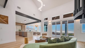 Un salón espacioso con un sofá verde, una mesa de centro de madera y un comedor con vistas al exterior.
