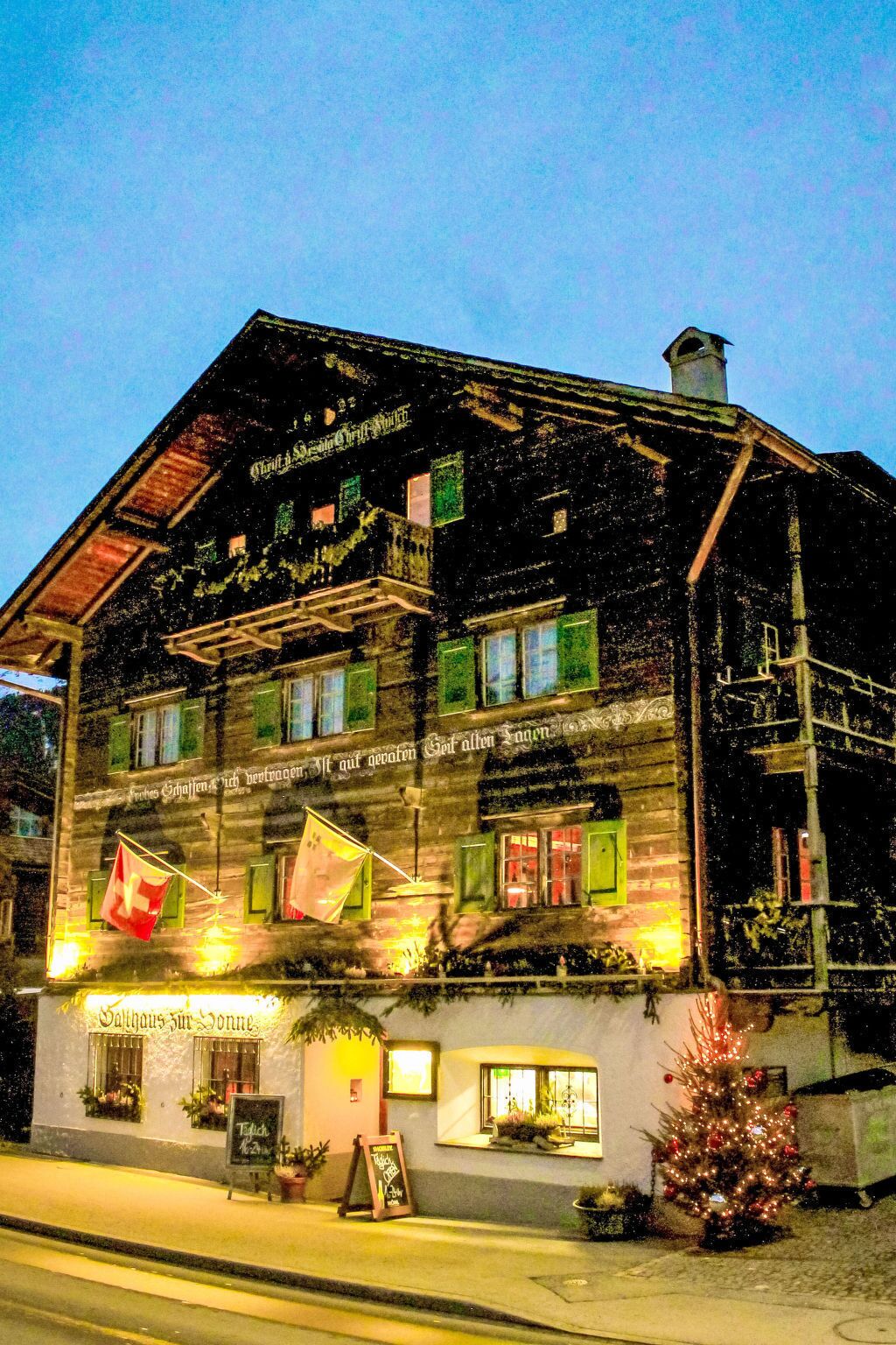 A traditional wooden building with multiple windows and a balcony, featuring signage in a foreign language.