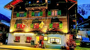 Un edificio de madera tradicional con múltiples ventanas, un letrero que indica que es un restaurante y una bandera en la entrada.