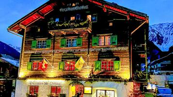 Un bâtiment traditionnel en bois, doté de nombreuses fenêtres, d’une enseigne indiquant qu’il s’agit d’un restaurant et d’un drapeau devant l’entrée.