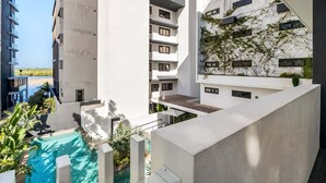 Un hôtel moderne doté d’une piscine sur le toit, de nombreux balcons et offrant une vue sur la plage.