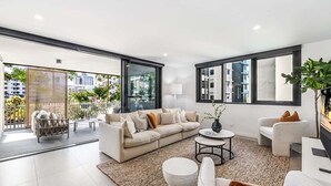 Un salon moderne avec un grand canapé, une table basse et une vue sur la ville grâce à de grandes fenêtres.