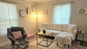 A living room with a grey armchair, a white sofa, a coffee table, and a floor lamp. - Cleanest Cottage in the County! (Pets Welcome) (Crestview)