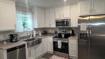 Una cucina moderna con mobili bianchi, elettrodomestici in acciaio inossidabile e forno a microonde integrato.