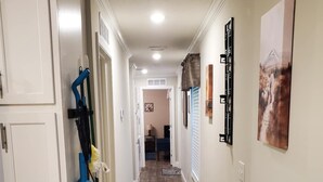 A hallway with white cabinets, a blue cleaning tool, and a framed picture on the wall.