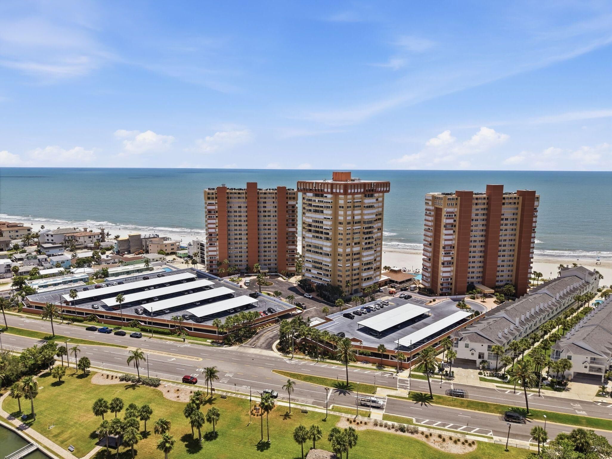 A coastal hotel complex with multiple high-rise buildings, a parking area, and a view of the beach.