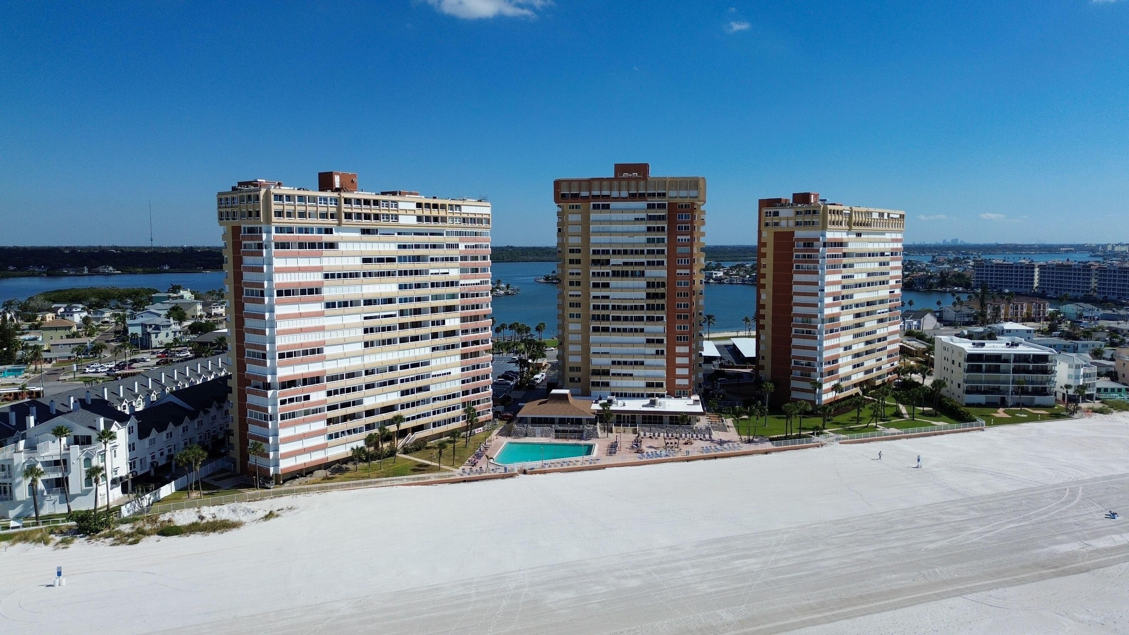 A high-rise hotel with multiple floors, a pool area, and a beach view.
