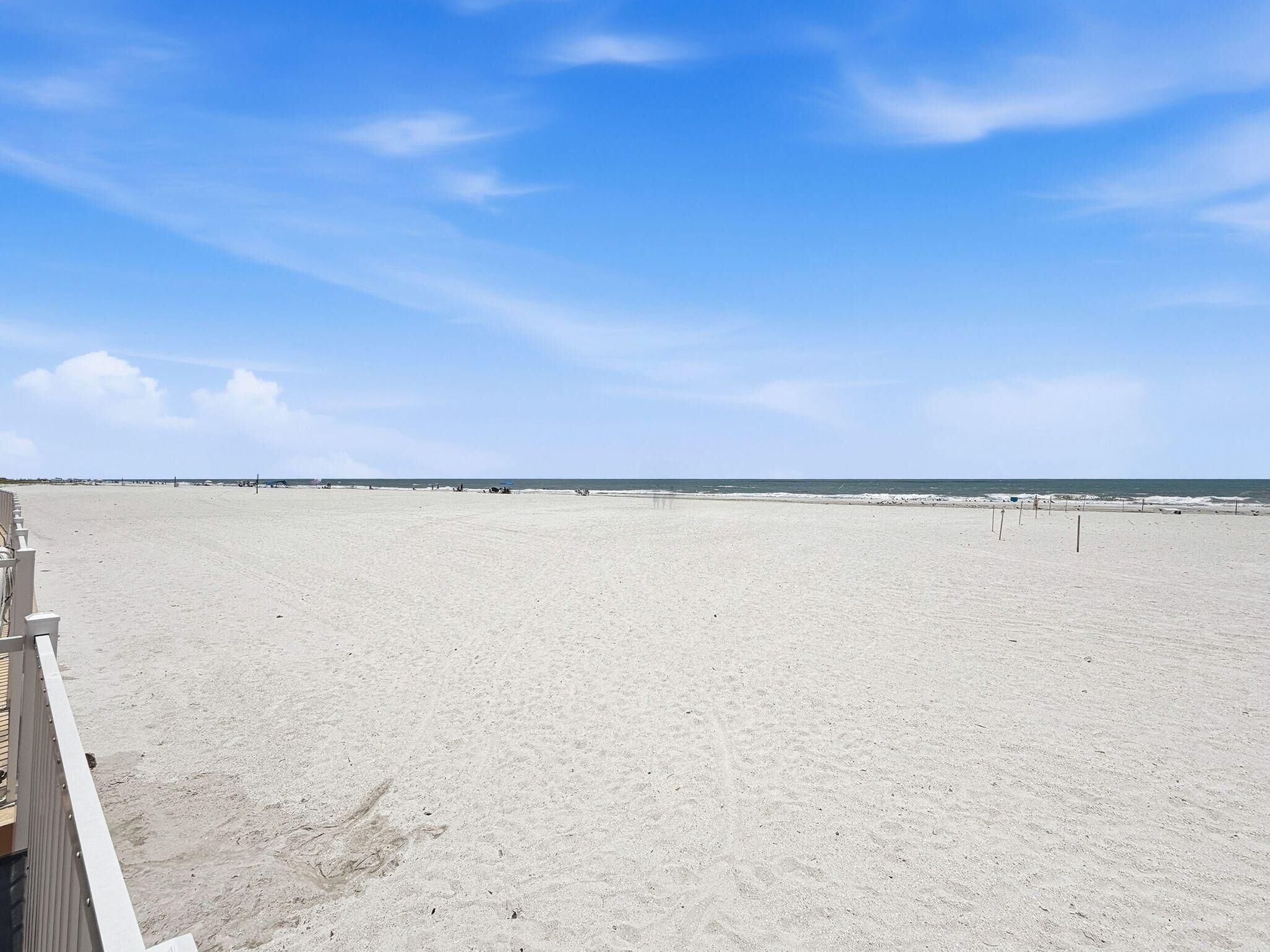 A beach with a clear sky, a sandy shore, and a wooden walkway.
