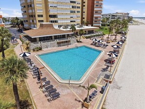 Een resort met een groot zwembad, ligbedden en uitzicht op het strand.
