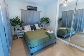 A bedroom with a bed, two bedside tables, a mirror, and two potted plants. - Villa Verde - Scenic Views of El Yunque Rainforest (Río Grande)