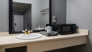 Une salle de bain équipée d’un lavabo, d’un miroir, d’un porte-serviettes et d’un four à micro-ondes.