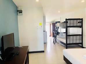 Una camera d'albergo con letti a castello, una scrivania con un computer e una televisione.