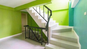 Una escalera con peldaños blancos y barandillas negras en una habitación con paredes verdes.