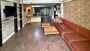 Un interior amplio con una pared verde, una pared de acento de ladrillo, un sofá de cuero y una mesa de centro de madera.
