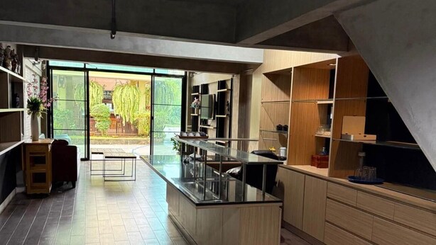 Cocina moderna con armarios de madera, una isla central y un ventanal con vistas a la vegetación.
