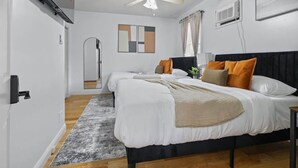 Une chambre d’hôtel avec un lit, un ventilateur de plafond, une télévision et une porte.