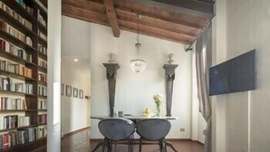 A room with a dining table, two chairs, a bookshelf, and a TV mounted on the wall. - Pitti Luxury Terrace by Mmega (Florence)