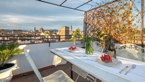 A terrace with a table set for two, overlooking a cityscape with historic buildings. - Pitti Luxury Terrace (Florence)