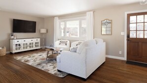A living room with a sofa, a TV, a cabinet, and a window. - The Rustic Retreat (Castle Rock)