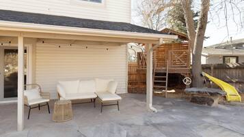 A covered patio area with a white sofa, two chairs, and a small round table.