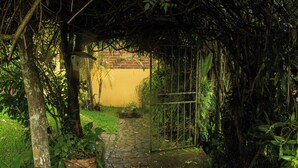A stone pathway leading through a lush garden with potted plants and a metal gate. - Colonial-Styled Hotel Villa in Ataco at 1,200 AMSL - 12 Rooms & Cabins available (Concepción de Ataco)