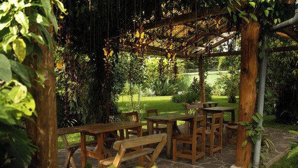 An outdoor wooden pergola with tables and benches, surrounded by lush greenery and a stone pathway. - Colonial-Styled Hotel Villa in Ataco at 1,200 AMSL - 12 Rooms & Cabins available (Concepción de Ataco)