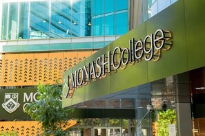 Un edificio con fachada verde y el texto 'Monash College' visible.